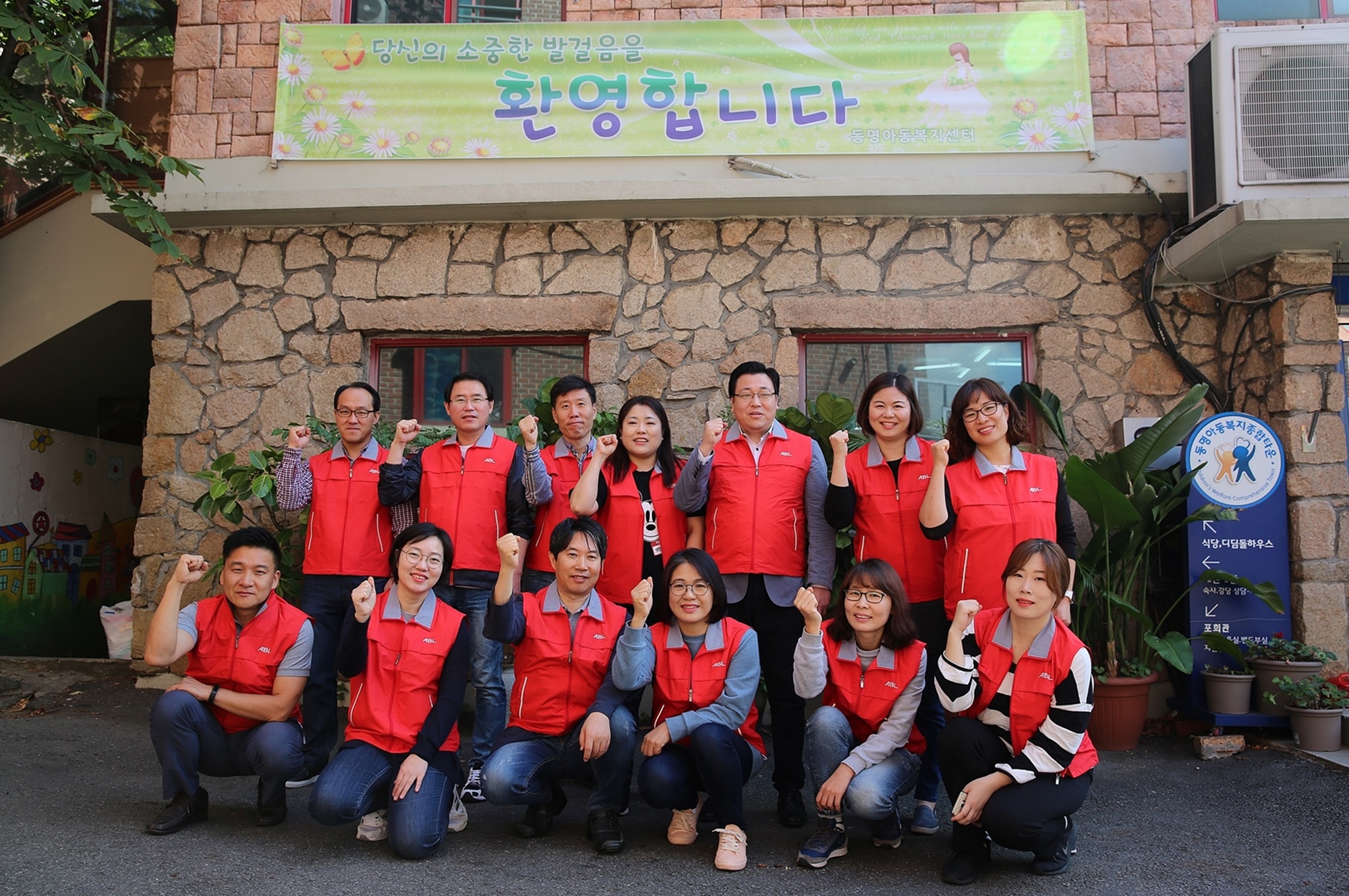 동명아동복지센터 입구에서 봉사활동 참가 직원들이 모여 찍은 단체사진